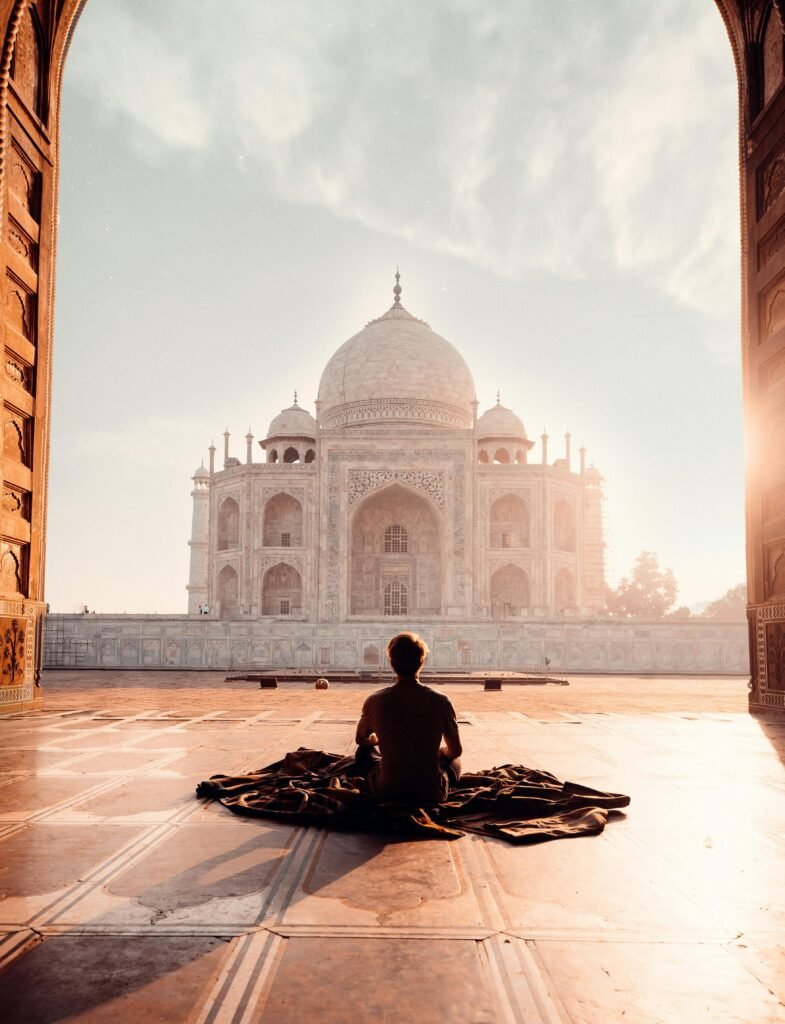 pexels-photo-2387871-2387871 A person meditates at sunrise facing the iconic Taj Mahal, capturing serenity and majesty.